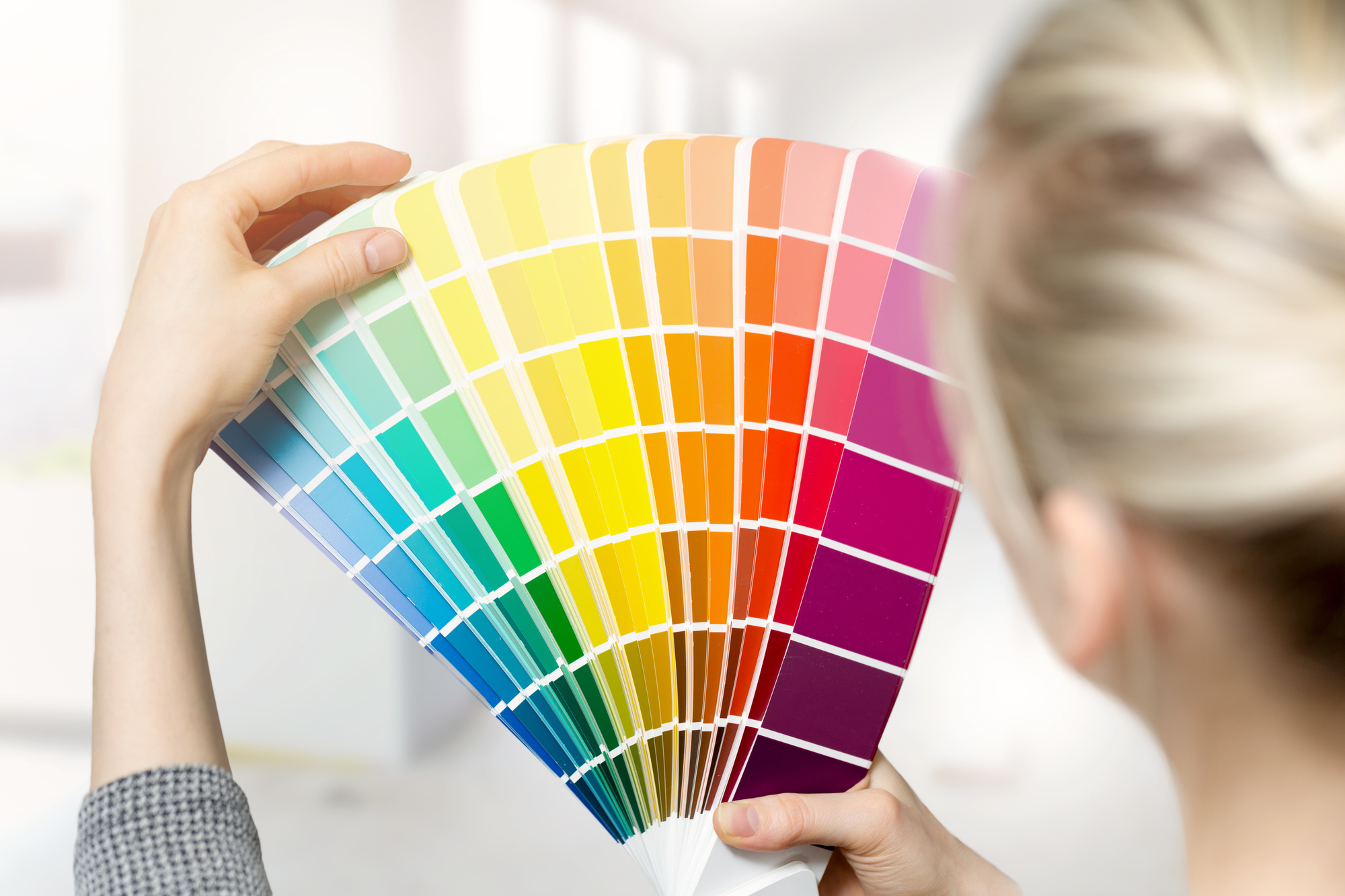 woman selecting home interior paint color from swatch catalogue